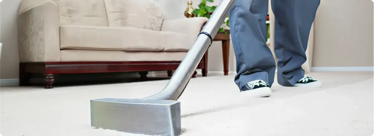 Carpet cleaning technician using a hot-water extraction wand on a light-colored carpet in a living room, Irvine, CA.