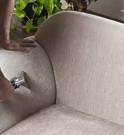 Professional upholstery cleaner deep-cleaning a fabric sofa with a handheld extraction tool and hose Irvine, CA.